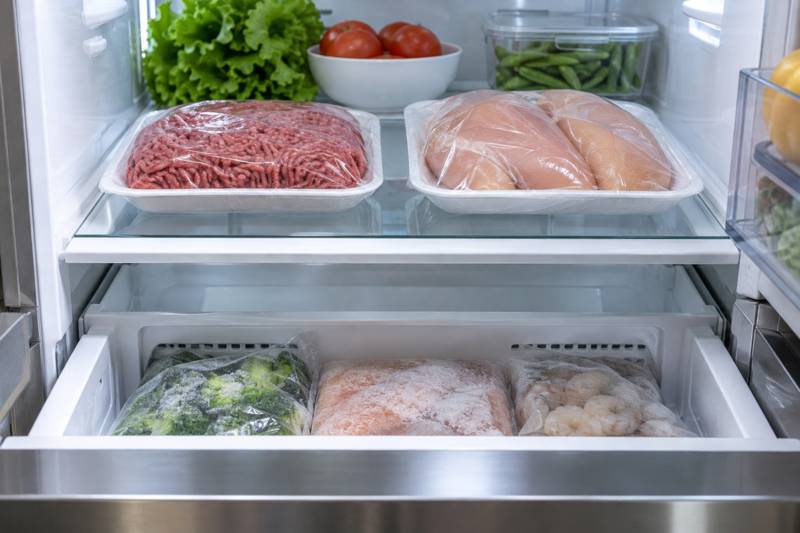 Packages of thawed raw meat on a refrigerator shelf, ready to be refrozen.